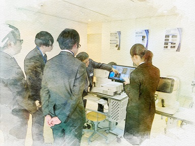 社内で新人社員が実機を使った研修を受け、業務スキルを身につけている様子。TOMEYの丁寧な教育体制と現場に近い学びの環境が伝わる場面。
